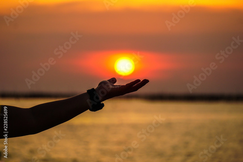 Sunset with the sun resting on the palm of a hand