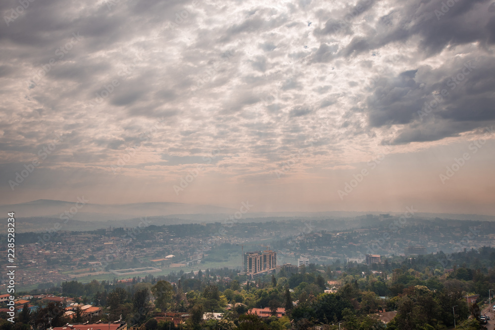 Fototapeta premium Sunlight breaks through the clouds over the hills of Rwanda that stretch into the distace