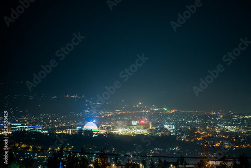 A wide view of city lights on the hills at night, with Kigali Convention Centre lit up in the colours of the Rwandan flag