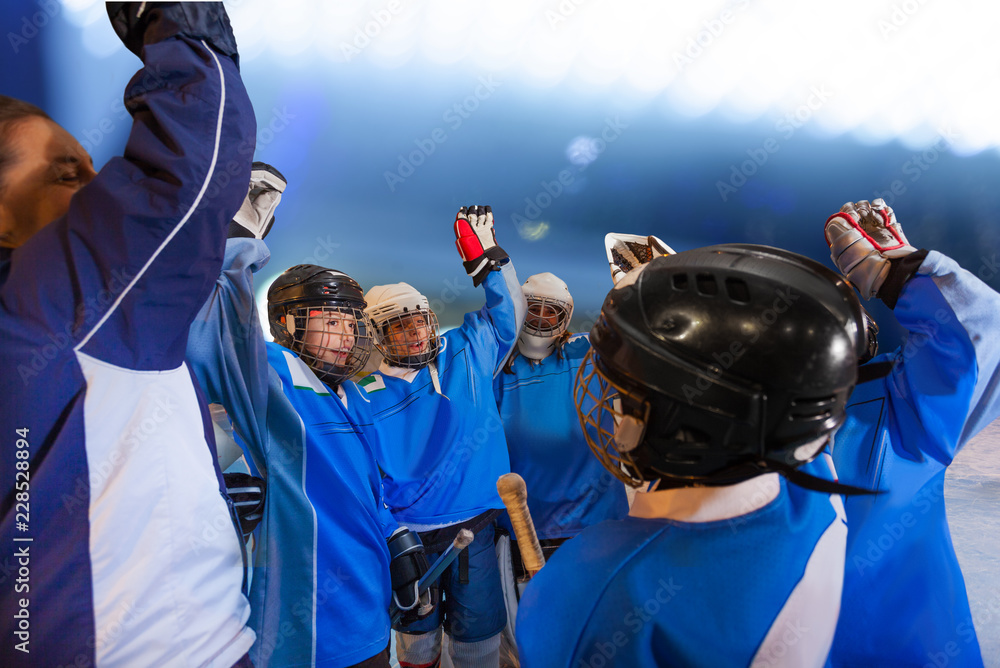 Fototapeta premium Coach and hockey players doing team cheer on rink