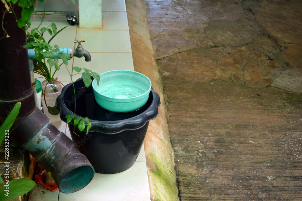 the black water bucket on tile floor with old faucet and big hole of drain tube at the local house of thailand the black water bucket on tile floor with old faucet and big hole of drain tube at the local house of thailand