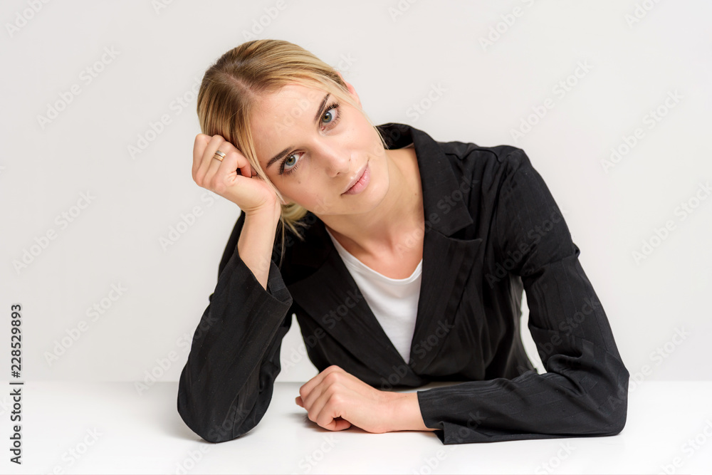 Studio photo of a beautiful blonde girl talking on a white background at the table. Studio photo of a beautiful blonde girl talking on a white background at the table.