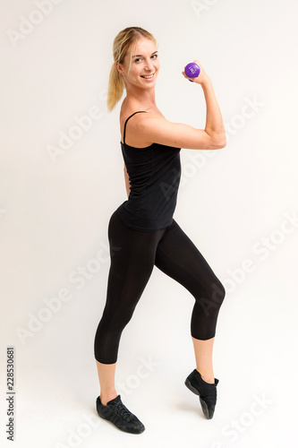 Studio photo of a beautiful blonde girl doing fitness stretching exercises on a white background.