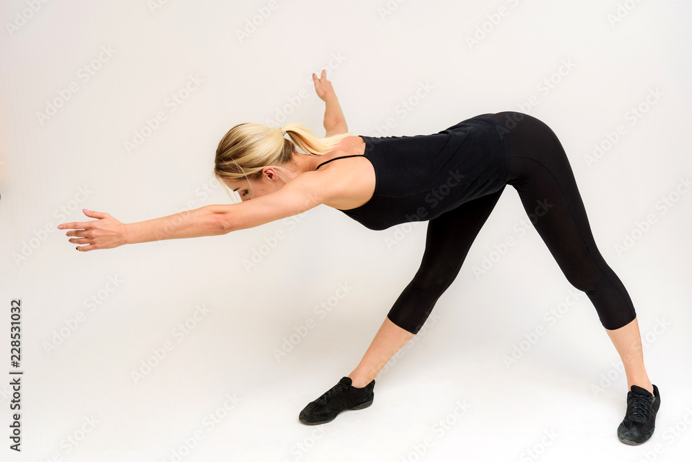 Studio photo of a beautiful blonde girl doing fitness stretching exercises on a white background.