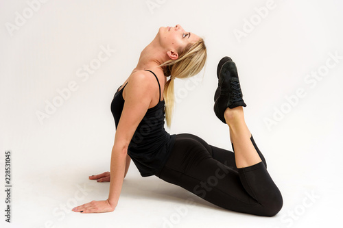 Studio photo of a beautiful blonde girl doing fitness stretching exercises on a white background. photo