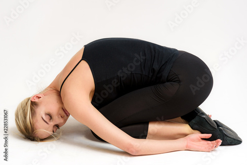 Studio photo of a beautiful blonde girl doing fitness stretching exercises on a white background.