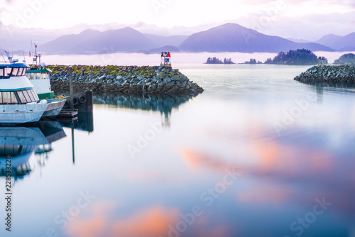 seascape sitka alaska, waterfront reflected sunrise colors on water. a coastal village with fishing and cruise vessels, mountains and sea smoke in background photo