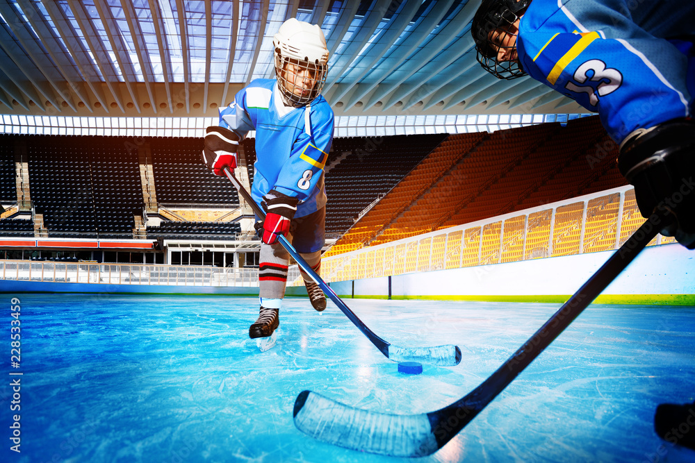 Fototapeta premium Hockey players challenging for puck on ice rink