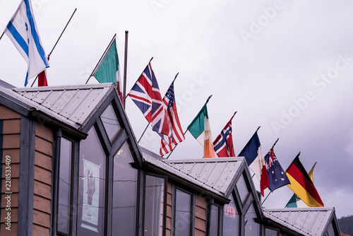 Flags of the world on top of a restaurant in Alaska USA. Colorful symbols with grey sky background. 