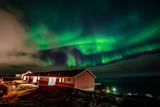 Green bright northern lights hidden by the clouds over living houses at the fjord, Nuuk city, Greenland