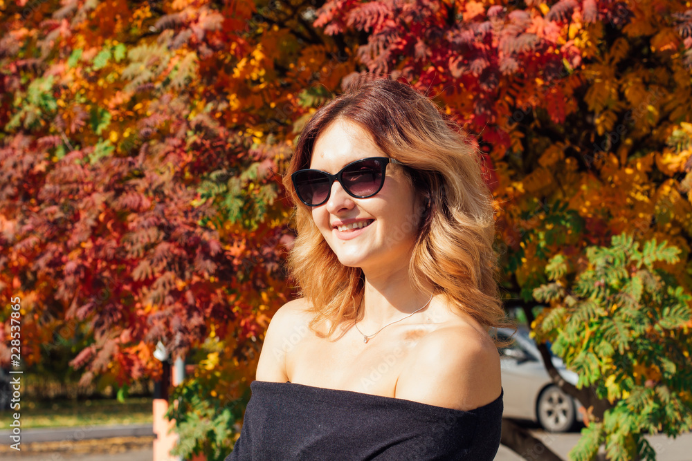 Charming woman in a black dress and sunglasses in the autumn park Charming woman in a black dress and sunglasses in the autumn park