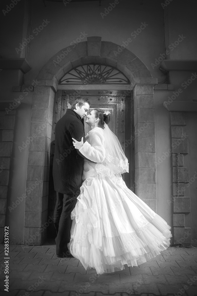 The bride and groom are watching each other on the old city street. Black and white image. The bride and groom are watching each other on the old city street. Black and white image.