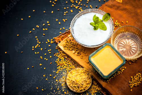 Herbal and organic home remedy for hair fall i.e. Egg white mixed with curd and fenugreek seeeds in a bowl,On wooden surface with raw fenugreek or methi seeds and curd with egg shells,Close up view. photo