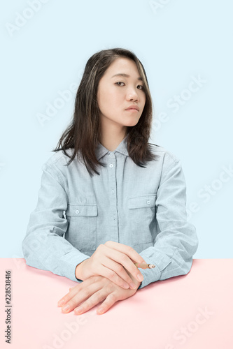 Handsome young korean women smoking cigar while sitting at table at studio. Trendy colors