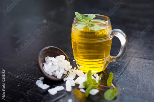 Close up of refreshing mint and lemon cooler in a transparent glass on wooden surface with raw lemon and juice and sugar. photo