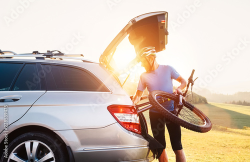 Man taking his bicycle out from the trunk of a car photo