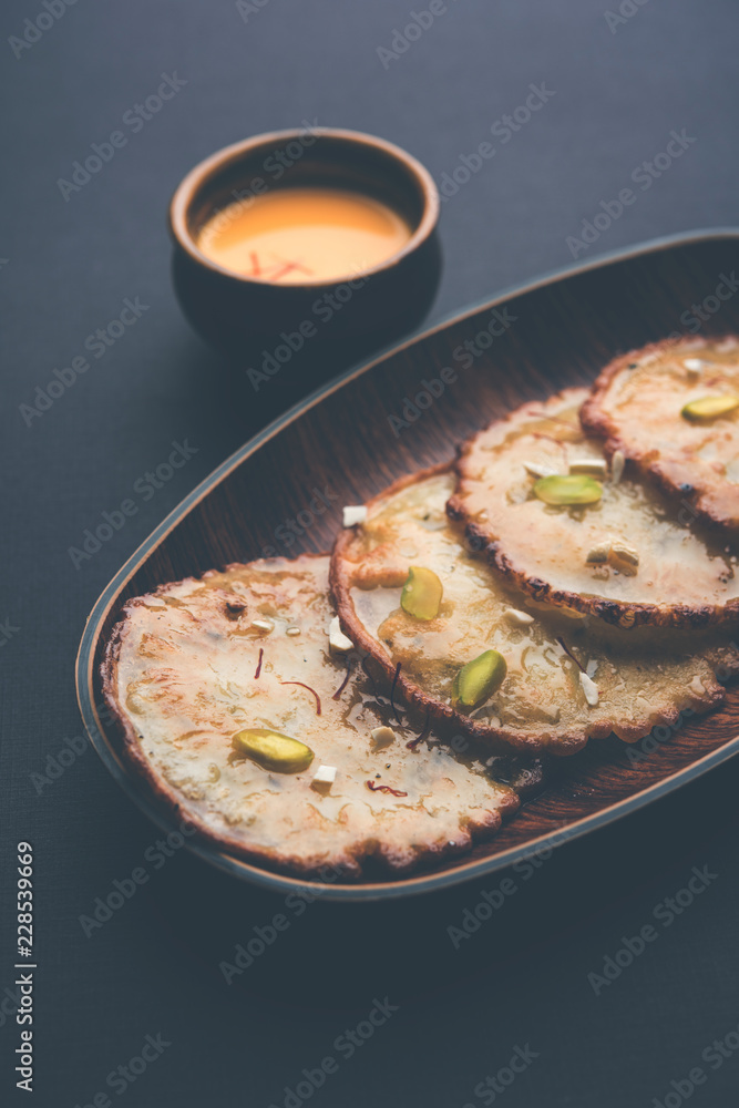 Malpua sweet - Traditional Indian dessert or pancake for festivals, served in plate with rabri/rabdi . selective focus Malpua sweet - Traditional Indian dessert or pancake for festivals, served in plate with rabri/rabdi . selective focus