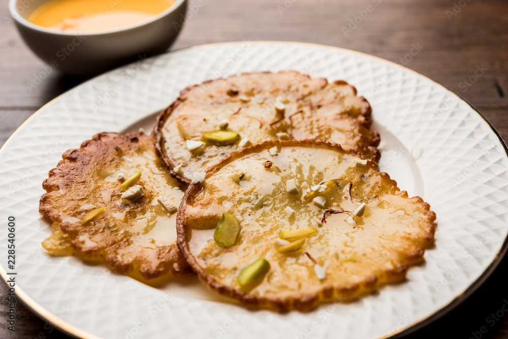 Malpua sweet - Traditional Indian dessert or pancake for festivals, served in plate with rabri/rabdi . selective focus Malpua sweet - Traditional Indian dessert or pancake for festivals, served in plate with rabri/rabdi . selective focus