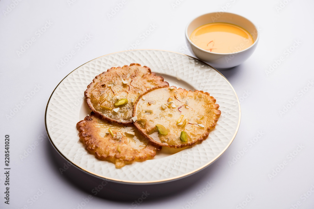 Malpua sweet - Traditional Indian dessert or pancake for festivals, served in plate with rabri/rabdi . selective focus Malpua sweet - Traditional Indian dessert or pancake for festivals, served in plate with rabri/rabdi . selective focus