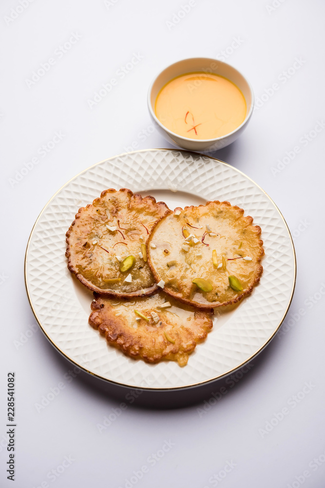 Malpua sweet - Traditional Indian dessert or pancake for festivals, served in plate with rabri/rabdi . selective focus Malpua sweet - Traditional Indian dessert or pancake for festivals, served in plate with rabri/rabdi . selective focus