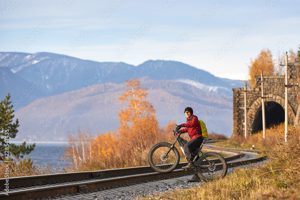 Obraz premium Tourist rides a bike with wide wheels along the shore of Lake Baikal.