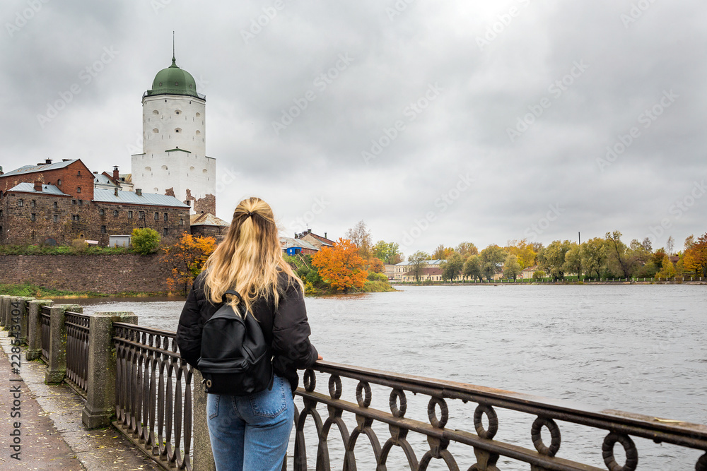 young female tourist watching the old town of Vyborg near the river
