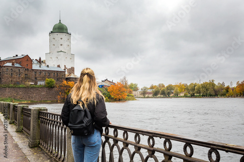 young female tourist watching the old town of Vyborg near the river