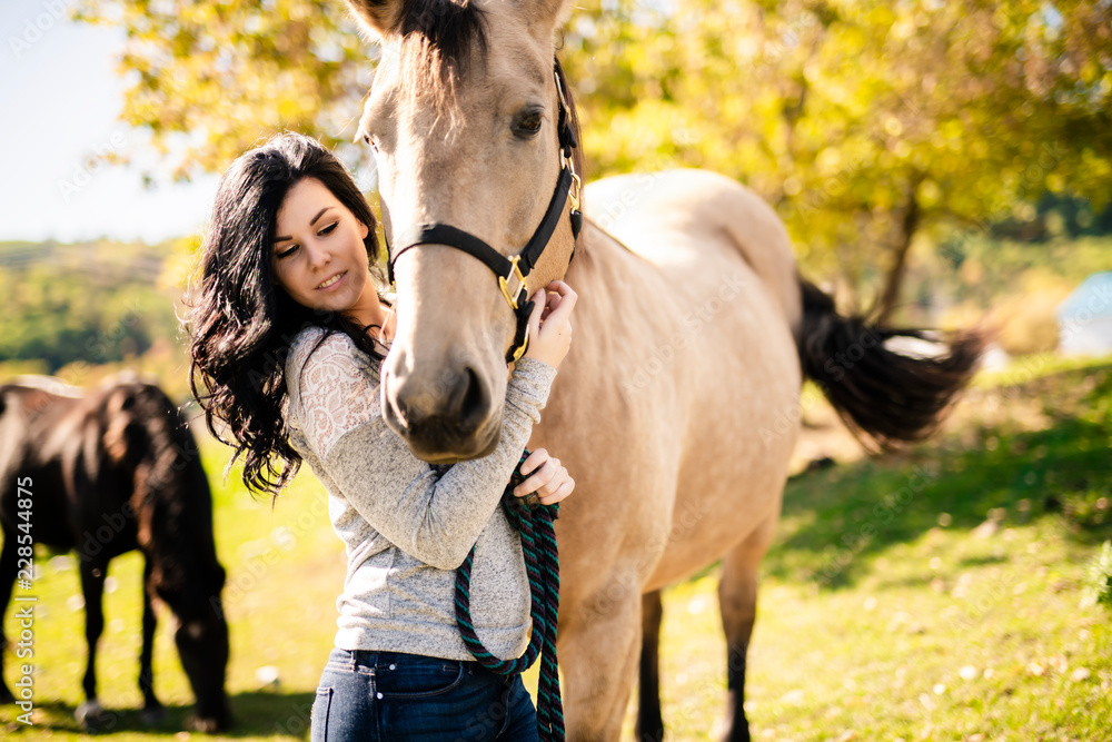 Obraz premium A Portrait of young beautiful woman with brown horse outdoors