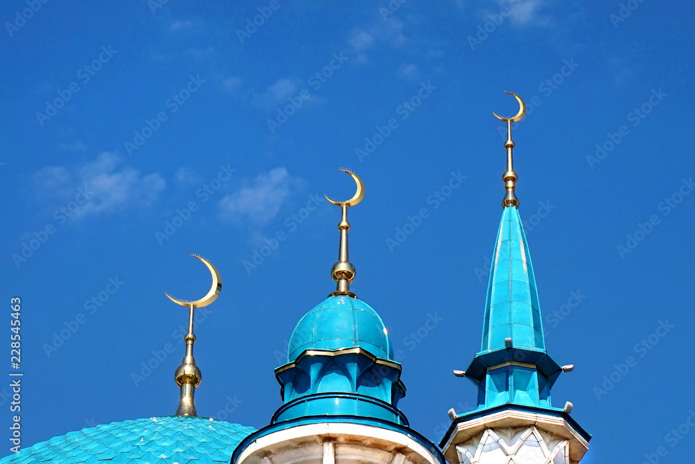 Mosque. Domes 3 crescents against a blue sky.