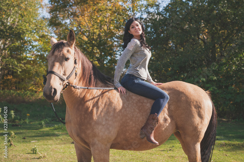 A Portrait of young beautiful woman with brown horse outdoors