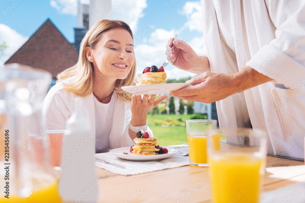 Surprised woman. Happy family woman feeling surprised and pleased while watching her husband serving breakfast Surprised woman. Happy family woman feeling surprised and pleased while watching her husband serving breakfast