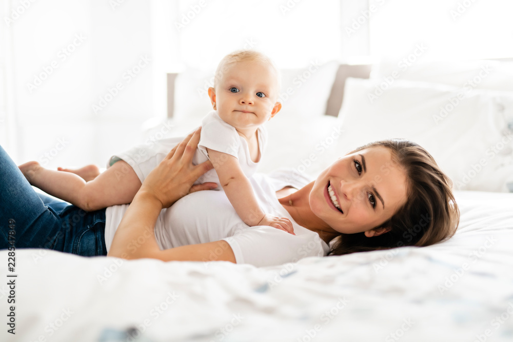 mother with baby on bed having good time mother with baby on bed having good time