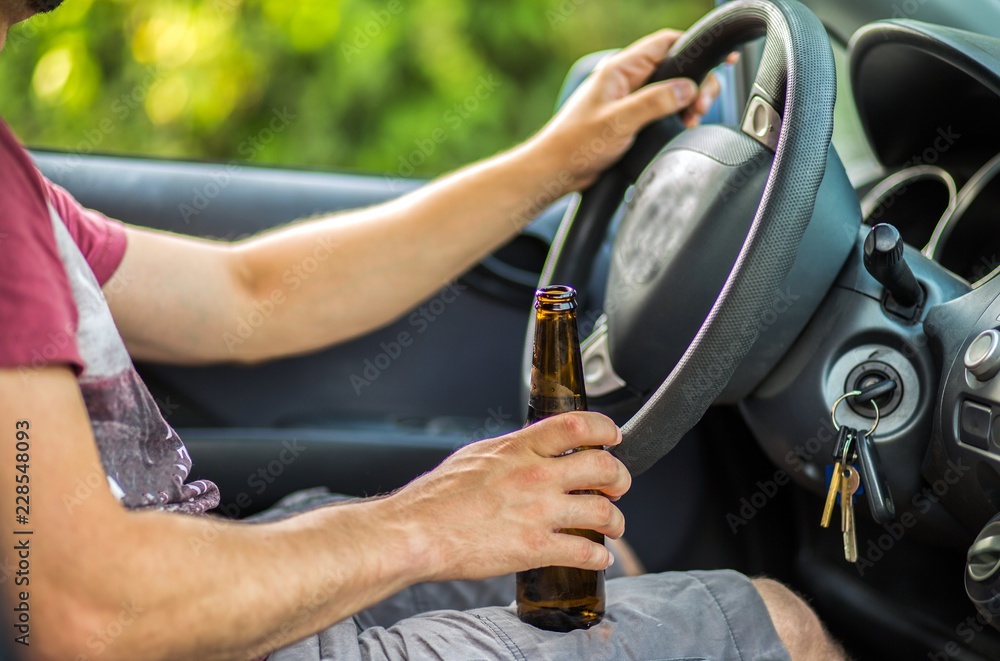 Man drinking alcohol while driving a car Man drinking alcohol while driving a car