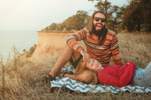 Hipster couple chilling and hugging on blanket on rocky coast with seaview © Vaobullan