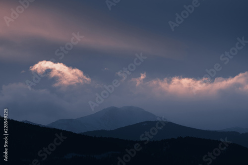 Dramatic winter storm blows over a cold barren landscape at sunset