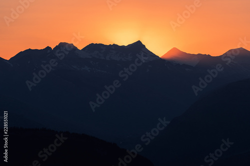 Panorama of Dramatic sun rays as the sun sets behind Heaven's Peak and Livingston Range, in Glacier National Park, Montana