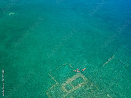 Aerial drone bird's eye view photo of tourists snorkeling above old Sunken City of Epidauros, Greece © Max Topchii