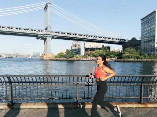 Young athletic woman jogs along the water in New York City