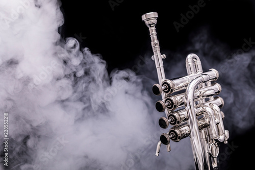 A silver plated piccolo trumpet in smoke on a black background photo