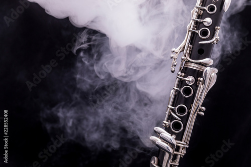 A black clarinet with silver plated keys in smoke on a black background photo