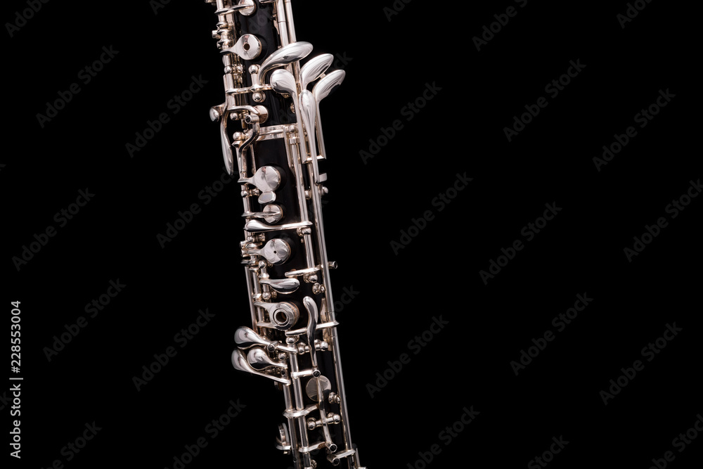 A black oboe with silver plated keys on a black background