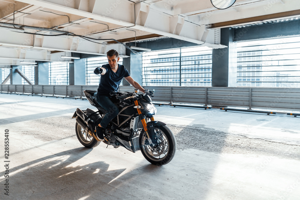 Distant plan of biker riding motorcycle at parking. Urban background.