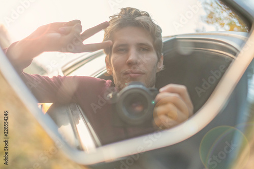 young driver taking a self portrait with professional camera in the car window f