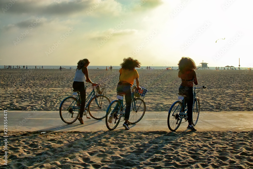 Fototapeta premium Three girls riding bikes on the strand in Santa Monica.