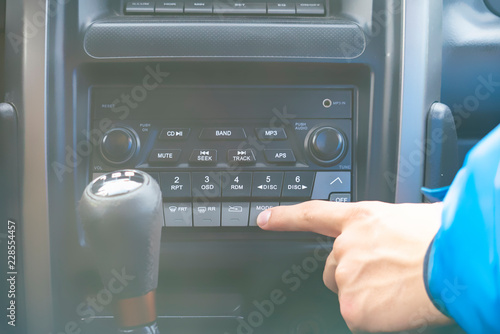 Slika na platnu close up person's hand push the car radio stereo system, searching for song f