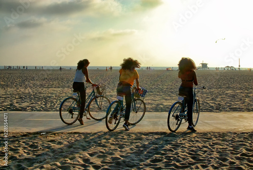 Three girls riding bikes on the strand in Santa Monica.