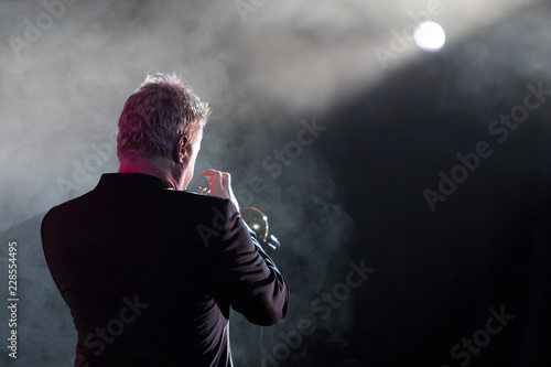 A trumpet player on stage with stage lights and smoke