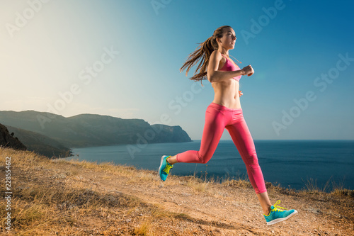 Woman running on mountain trail. Young runner jogging sneakers in a beautiful nature. Healthy lifestyle fitness.