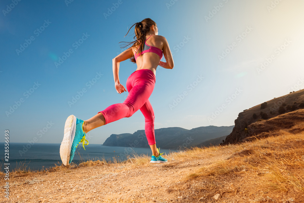Woman running. Young girl runner jogging on a mountain trail in