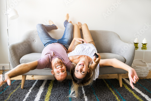 Young couple laying on the sofa with heads upside down